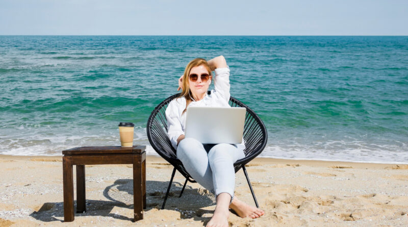 vista frontal da mulher com laptop trabalhando na praia criando conteudo para marketing digital