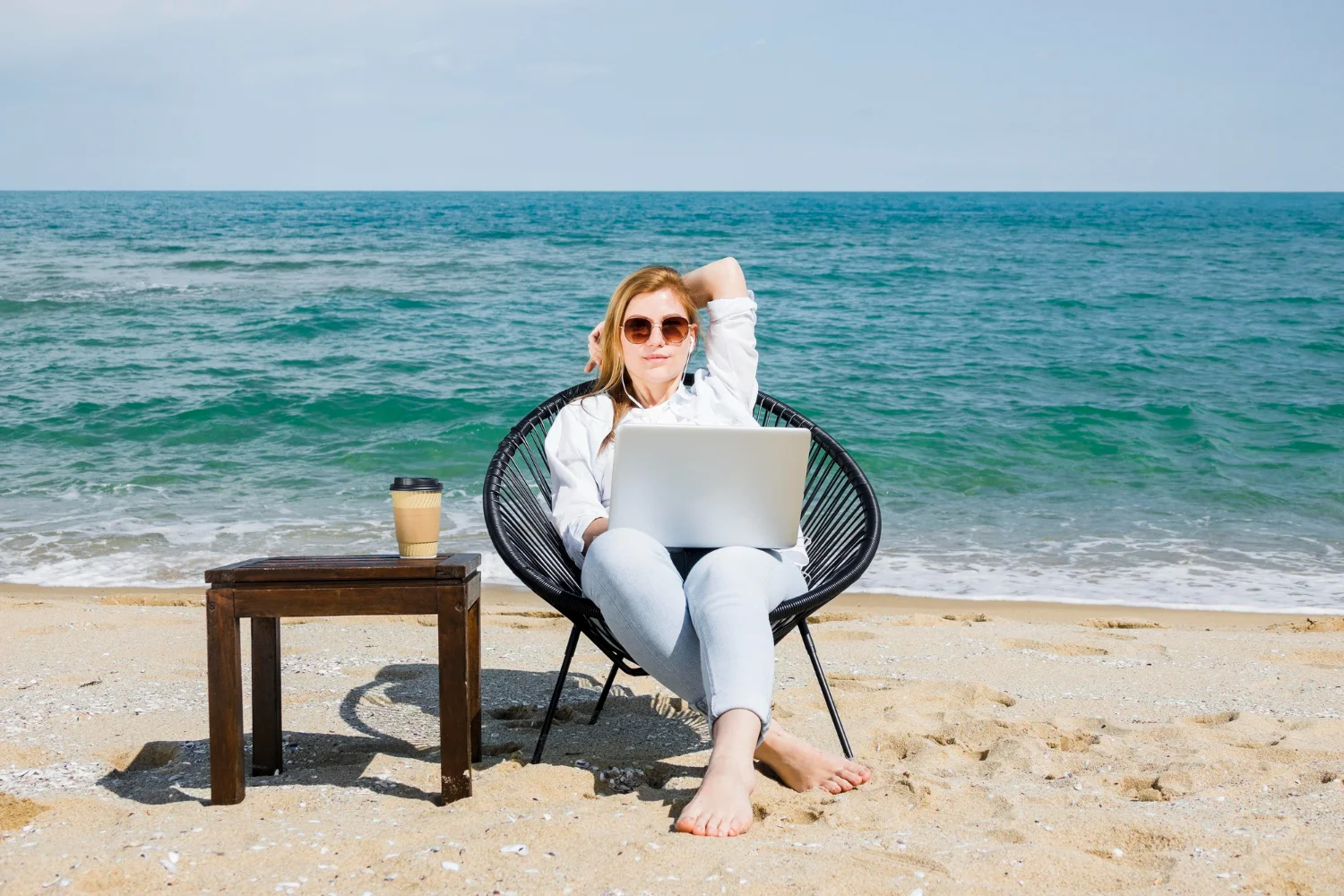 Guia Completo sobre Como Criar Conteúdo para Marketing Digital vista frontal da mulher com laptop trabalhando na praia criando conteudo para marketing digital